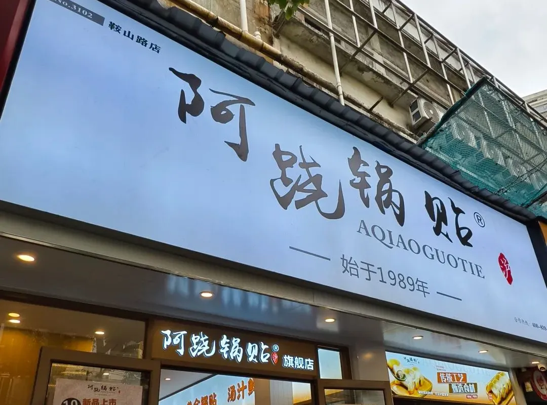 A narrow A Qiao Guotie storefront with its red sign above a Shanghai side street