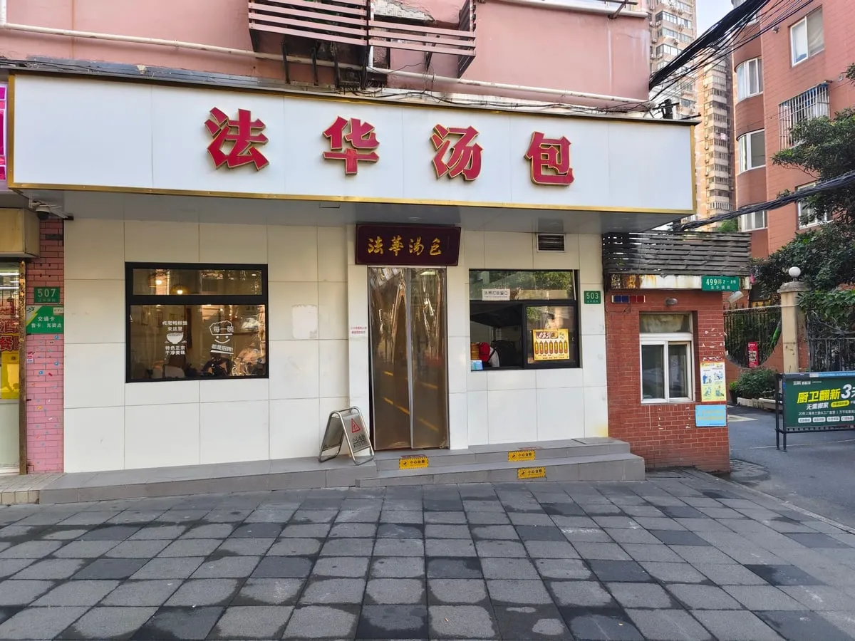 Fahua Tangbao’s white storefront and red Chinese sign at street level
